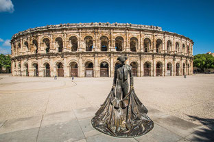 Photo des arènes de Nîmes avec une statue d'un matador