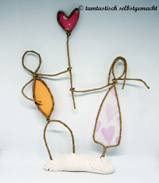 Papierdrahtfigur-Pärchen-Mann-und-Frau-halten-gemeinsam-ein-rosa-Herz