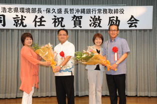 同級生より花束を受け取る保久盛長哲常務(右)と大浜浩志環境部長=18日夜、サザンプラザ海邦(那覇市)