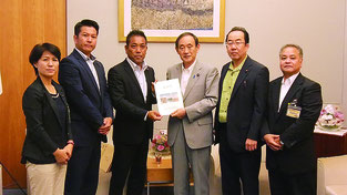 菅官房長官に要請書を手渡す八重山広域市町村圏事務組合議会の要請団(同議会事務局提供)