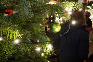 Tanne mit Lichterkette und grüner Christbaumkugel.