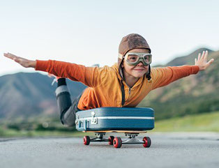 Junge rollt als Pilot auf Skateboard und Koffer