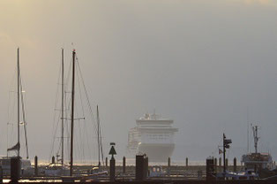 Dunst umhüllte Fähre beim Einlaufen in den Hafen, im Vordergrund Segelboote