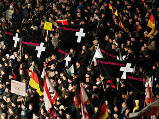 Pegida-Anhänger halten in Dresden Plakate mit den Namen der Opfer der Terroranschläge in Paris. Foto: Arno Burgi/Archiv