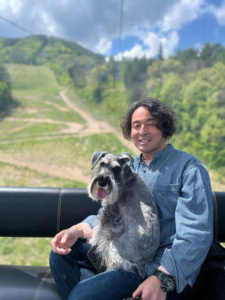 白馬岩岳マウンテンリゾートのリフトにミニチュアシュナウザーと一緒に山頂へ移動する男性