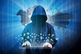 Hooded man with face in darkness typing at a keyboard with light blue colored numbers rising up over his hands. Streams of light and the dark shape of the world map are in the background. 