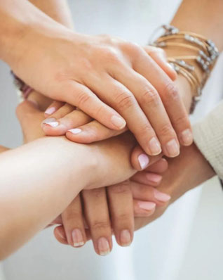 Mehrere Frauen legen ihre Hände übereinander – Symbol für Vertrauen, Verbindung und weibliche Gemeinschaft im Retreat Human Design & lebendige Weiblichkeit in Mecklenburg-Vorpommern