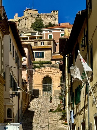 Tor mit alter Inschrift in Porteferraio auf Elba und dahinter eine Burg