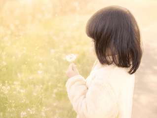 女の子がタンポポを見つめている