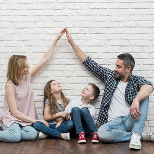 une famille avec 2 enfants sous une toit simulé par leurs parents