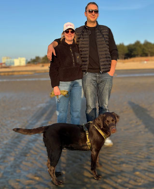 Das Bild zeigt ein Paar mit ihrem Hund Eddie am Strand von Saalenburg