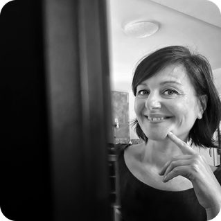 Petra Ouschan sitzt hinter einem Monitor und lächelt