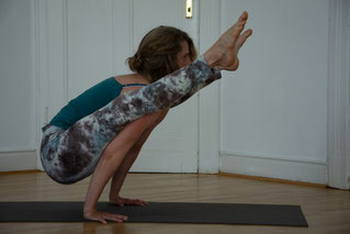 Jeannine übt Handbalance Tittibhasana aus der 2. Serie vor einer Altbau Holztuer