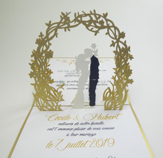 Faire-part de mariage en pop-up avec les mariés qui s'embrassent sour une arche fleurie doré