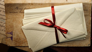 ein Bündel von Briefen, zusammengehalten von einem roten Satinband, auf historischen Papieren - Bild für meinen Briefkasten