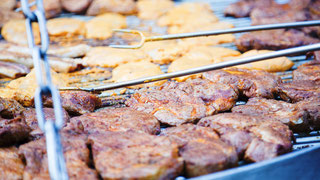 Ein Schwenkgrill mit Nackensteaks, Bauchspeck, Hähnchenbrustfilet und Putenfleisch gegrillt auf Buchenholz.