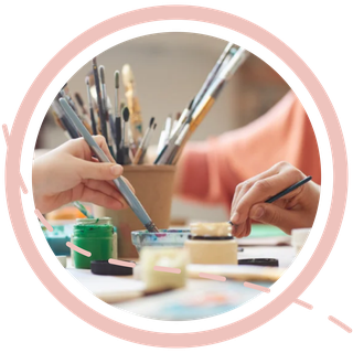 alt="Deux personnes en train de peindre ensemble dans un atelier, entourées de pinceaux et de pots de peinture — ambiance chaleureuse et créative d’un stage aquarelle en présentiel à Créteil."