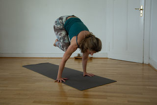 Jeannine übt Handbalance Bakasana aus der 2. Serie vor einer Altbau Holztuer