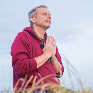 Eine Person meditiert ruhig in einer weiten Berglandschaft
