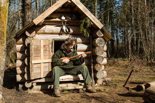 John C jouant de la dombra, devant une isba qu'il a construit en 2011