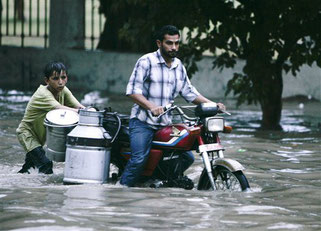 A Pakistani milk vendor pushes his motorcycle through water after heavy monsoon rain in Karachi, Pakistan on Tuesday, July 27, 2010. (AP Photo/Shakil Adil)