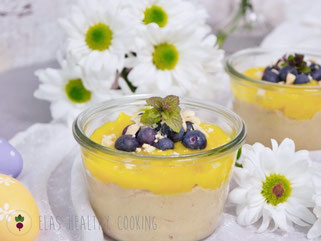 Veganer Hirsepudding im Glas mit Mangopüree, Heidelbeeren und gehackten Nüssen