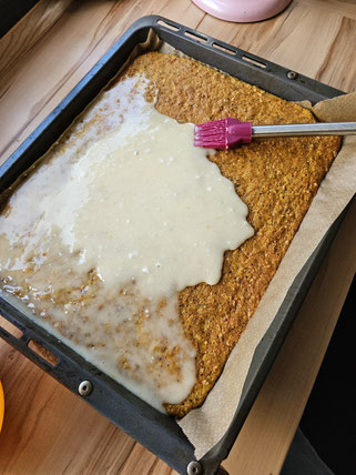 Zuckerguss auf dem fertig gebacken Teig für Rübli Schnitten verteilen