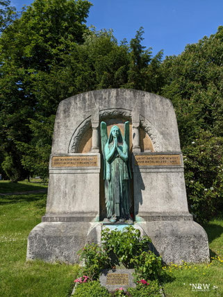 Grabmale und Bäume sind hier zu sehen.