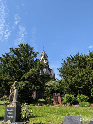Grabmale und Bäume sind hier zu sehen.