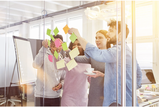 Workshop Teilnehmende kleben PostIts an die Wand