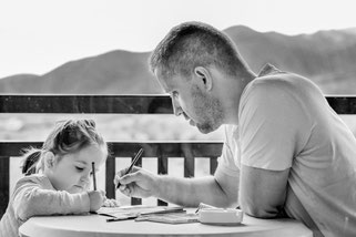 Vater und Tochter malen gemeinsam an einem Tisch