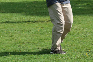 View of the legs of a Taiji practitioner who is walking the short form on a meadow. 