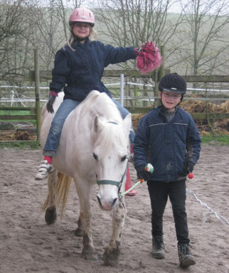 Zwei Kinder reiten auf einem Pony