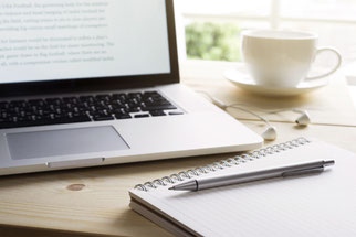 Laptop mit Notizblock und Stift