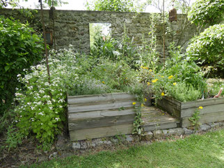 Üppig bepflanztes Hochbeet vor einer Natursteinwand. Naturgarten, Hobbygärtner, Kompost, Kräutergarten, Gemüsegarten, Schlüssellochgarten, Permakultur