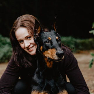 Ich sitze hinter meinem Dobermann und schaue in die Kamera, Arthos schaut nach links