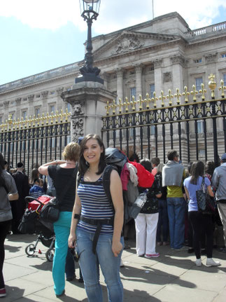 Johanna steht lächelnd mit einem Wanderrucksack vor dem Buckingham Palace