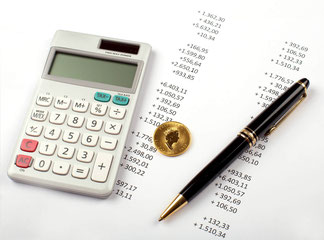 Ein Taschenrechner, ein Goldstück und ein Stift, die auf einem Additionsstreifen liegen.