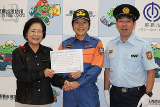 辞令を受けた大城さん(中央)と城間市長(左)、嘉数勝消防団長(右)=19日、サンエー那覇メインプレイス
