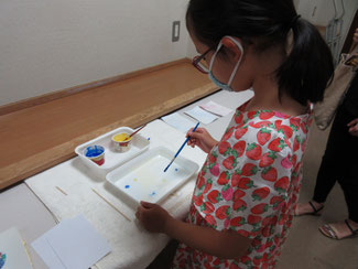 ①筆にアクリル絵の具をつけ、水面に触れるようにして絵の具を3か所程度落としていきます