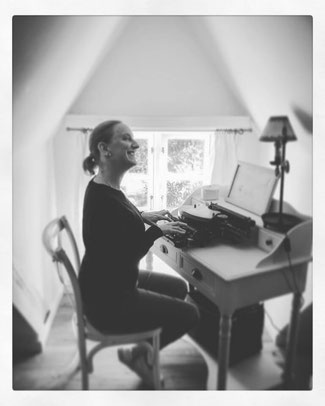 black and white photo of Louise sitting at a desk with a typewriter