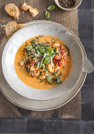 Herbstlicher Bohnen-Eintopf mit Spinat und getrockneten Tomaten in einer Schüssel serviert.