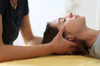 Therapeutin führt eine CranioSacrale Behandlung durch um der Patientin mit Kopfschmerzen und Nackenverspannungen die Symptome zu lindern.