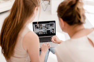 Zwei Frauen die miteinander am Laptop arbeiten.