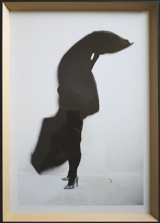 Letizia Rostagno, Il mio nome è notte #3, 2025. Silhouette femminile in movimento: il corpo è quasi interamente coperto da una massa di tessuto nero in torsione, visibili solo le gambe e le scarpe con tacco zebrate. Stampa digitale su Canson Platine Fibre