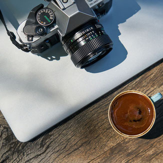 Appareil photo posé sur un ordinateur à côté d'une tasse à café