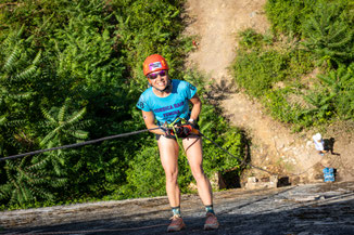 participante en descente en rappel sur paroi rocheuse vue plongeante en pleine nature lors d’une épreuve sportive outdoor