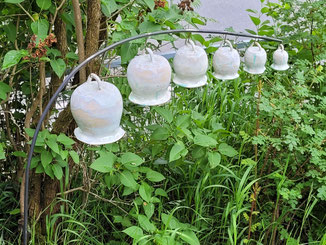 Glocken in sechs verschiedenen Größen an Metallstab in Garten