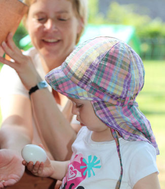 Familien mieten Hühner, Mutter mit Kind, Kind hält ein Ei