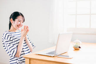 パソコン腰にカウンセリングを受けて笑顔担っている女性のイメージ写真